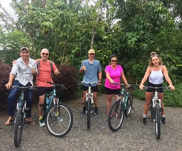 Travellers on a guided cycling tour along a leafy Bali back road