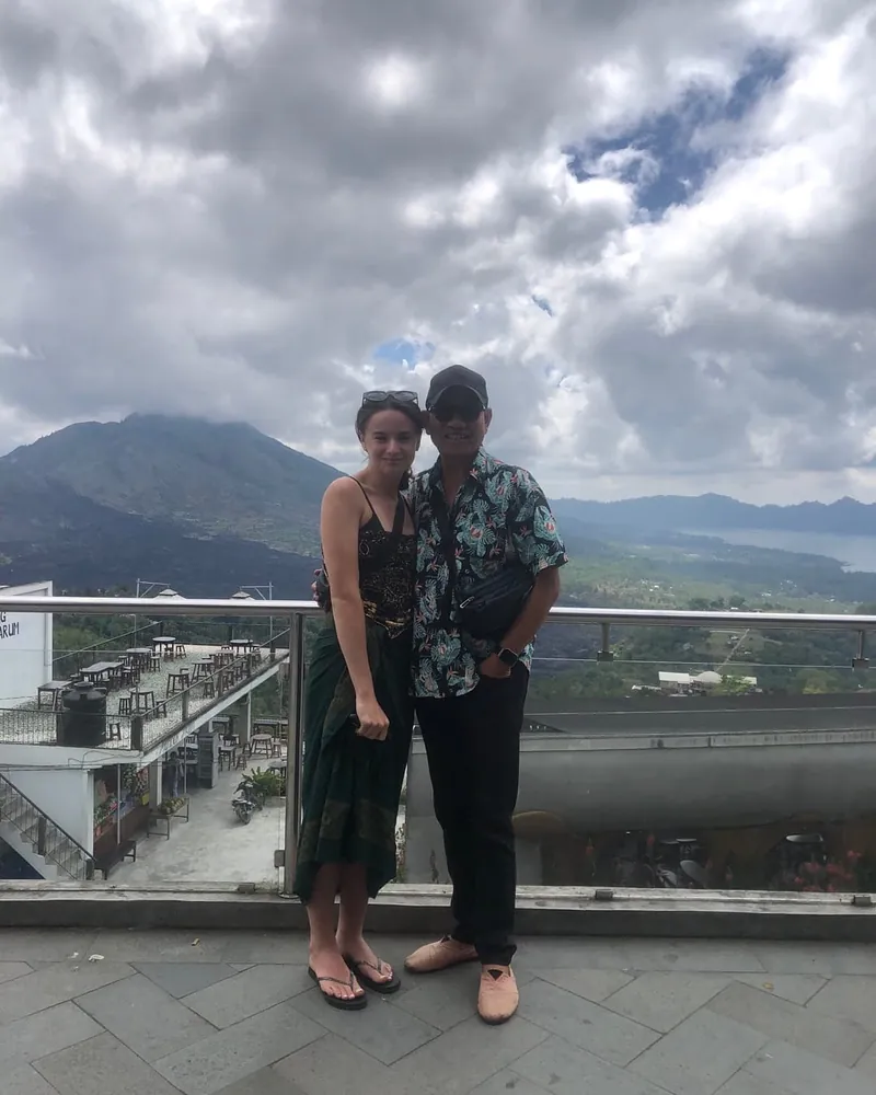 Travellers at a Mount Batur viewpoint with the volcano and caldera behind