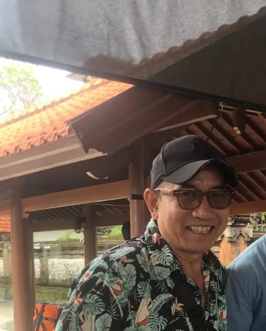 Ketut, your Balinese private driver and tour guide, smiling at a temple pavilion
