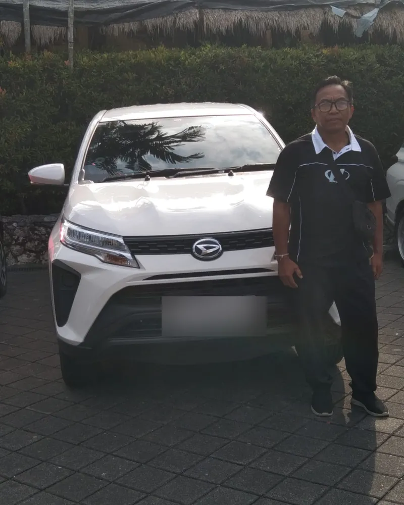 Ajik Ngurah standing beside his white Daihatsu Terios